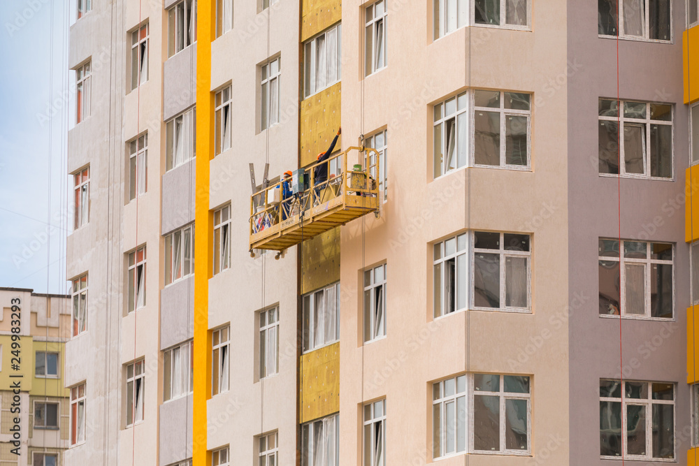 Builders paint the facade of a high-rise residential building Builders paint the facade of a high-rise residential building