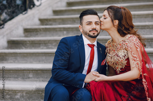 Photography Beautiful woman in a long red dress walks around the city with her husband in a
