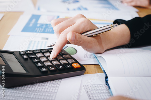 Businesswoman working on calculator to calculate business data the financial report on table.