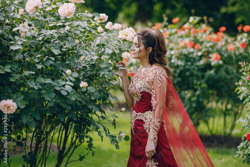 A beautiful Turkish girl in a long red dress walks in the summer old city A beautiful Turkish girl in a long red dress walks in the summer old city