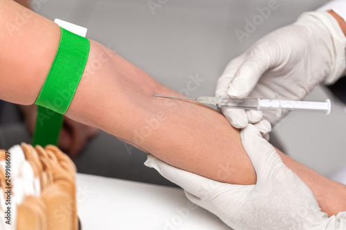 Arzt gibt eine intravenöse Spritze, Venenstauer um den Arm