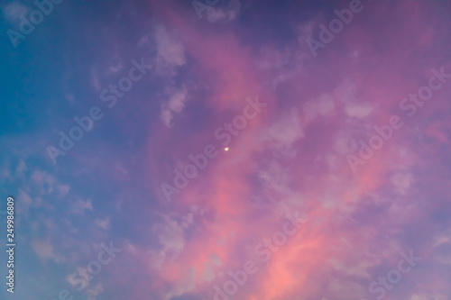 White moon on colorful vivid pink and blue twilight sky.