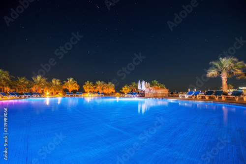 open pool on the shores of the exotic ocean and the reflection of palm trees in the water. summer landscape.night view