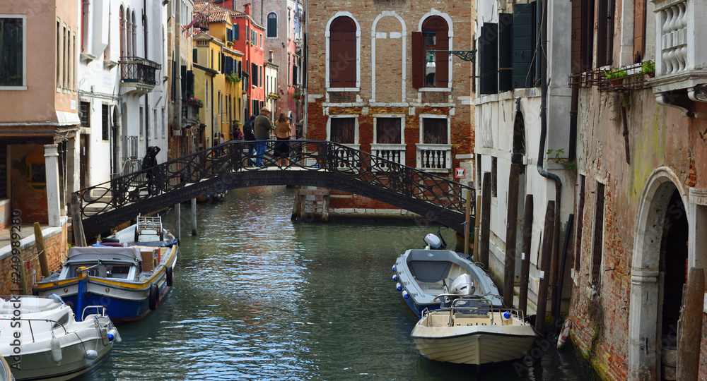 Small Venice Canal with Boats Bridge and People.