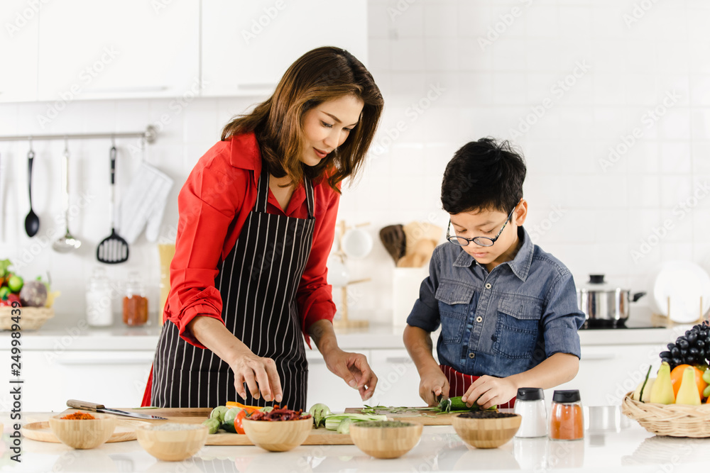 Asian mom in red shirt and black  apron is teaching her son.
