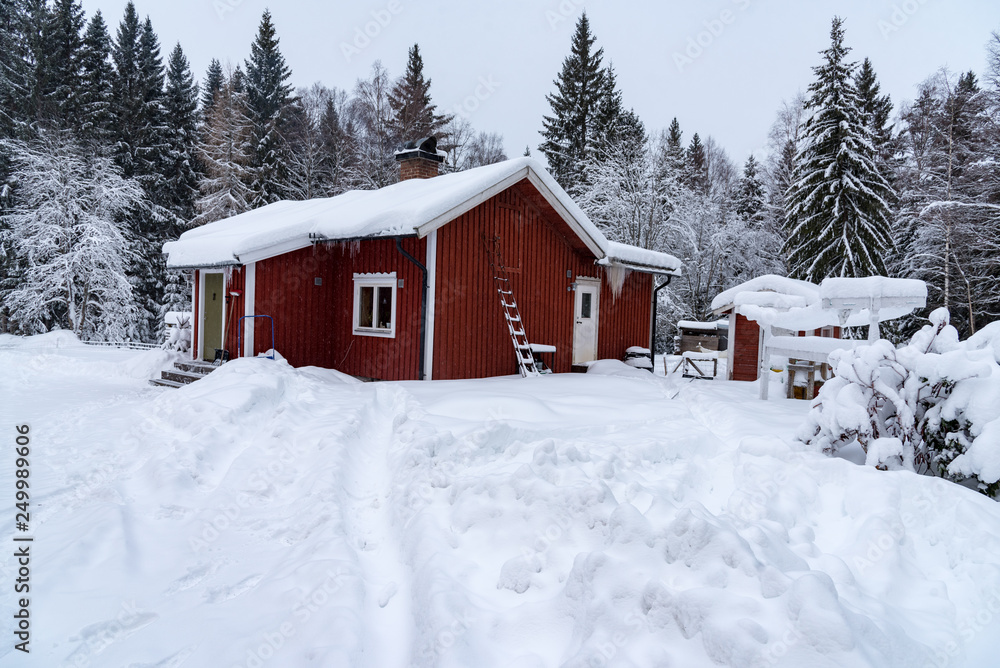 red cabin covered in snow in sweden