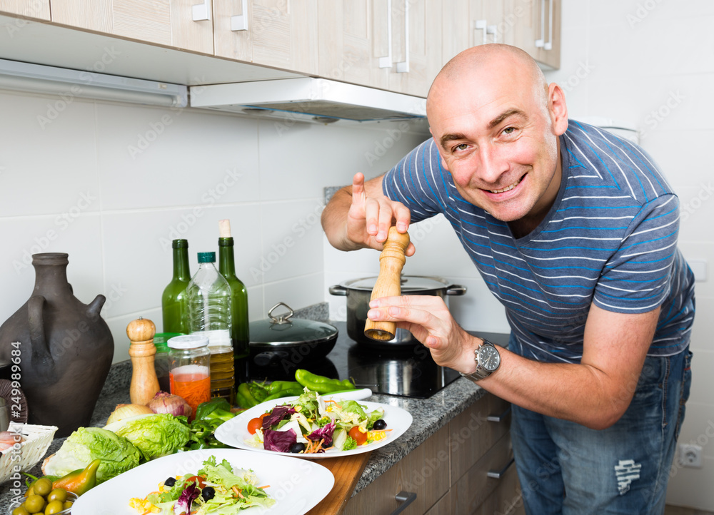 ordinary man sprinkle with pepper salad on plate ordinary man sprinkle with pepper salad on plate