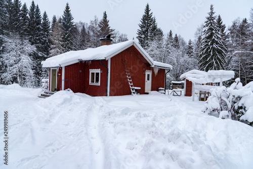 red cabin covered in snow in sweden © Jonas
