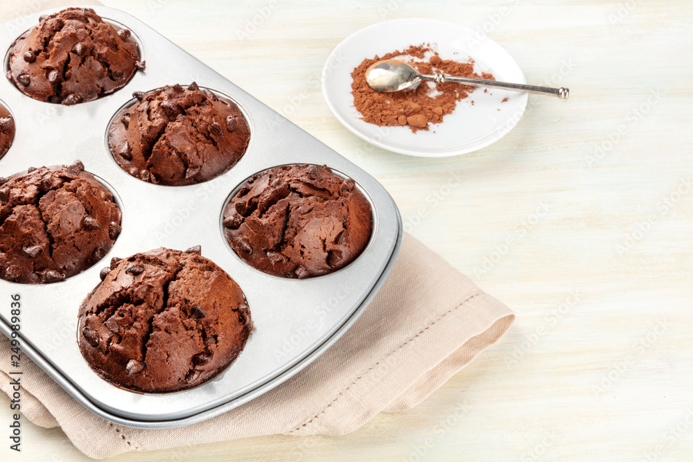 Φωτογραφία A photo of chocolate muffins in a mould on a light background with cacao powder