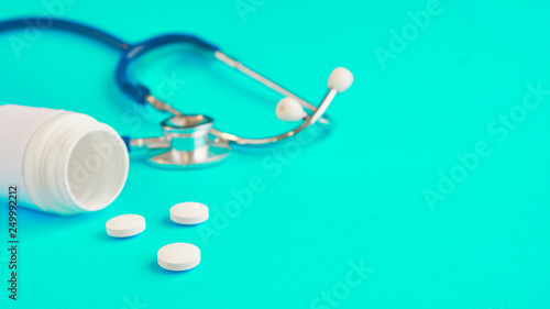 Aspirin and stetaskop on a blue background. white pills. how to get a drug