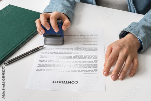 Business woman putting stamp on documents in the office