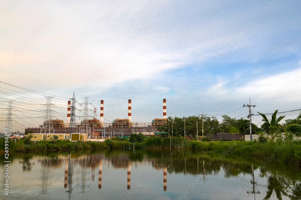 Natural gas electric power plant with smokestack and many pole in chonburi thailand with water reflection and beautiful sky near evening