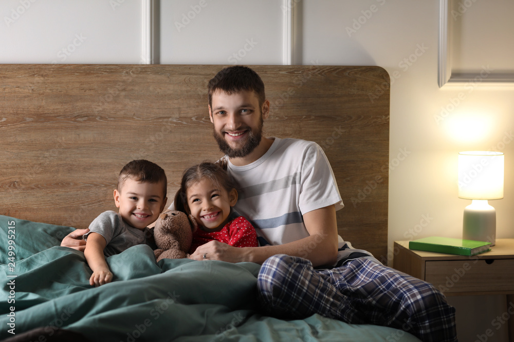 Portrait of happy father with his children in bed at home
