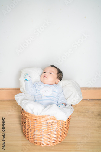 Infant baby lying on blanket in wood baket on white background