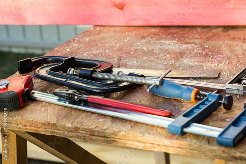 Composition of construction tools on an old wooden table of pliers, pipe wrench, screwdriver, clamps, roulette