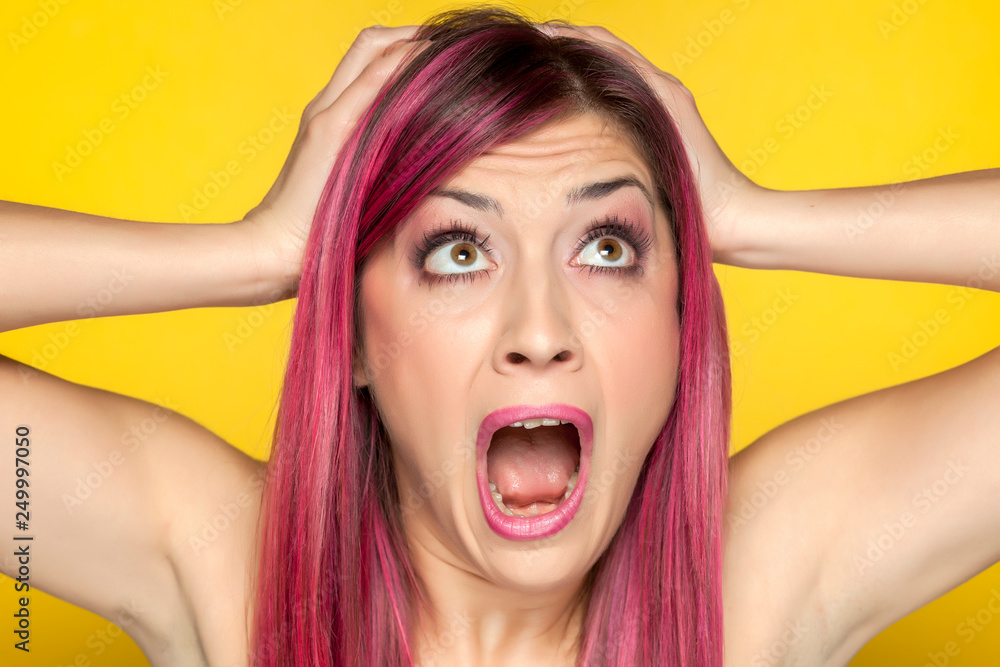 Young shocked woman with pink hair on yellow background Young shocked woman with pink hair on yellow background