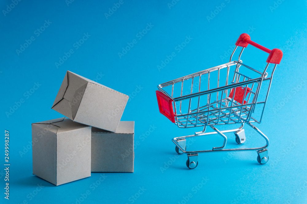 Shopping cart and box on blue background, business and shopping concept. Selective focus