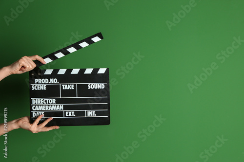 Female hands with cinema clapperboard on color background