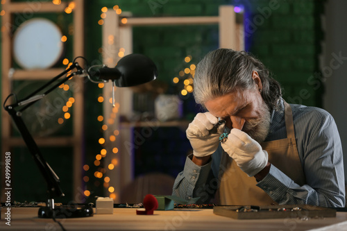 Jeweller examining adornment in workshop