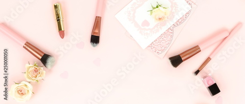 Makeup cosmetic accessories products banner. brushes, lipstick, pink flowers on pastel colors background. Flat lay. Top view. Copy space