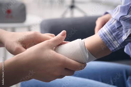 Woman applying bandage onto female arm, closeup