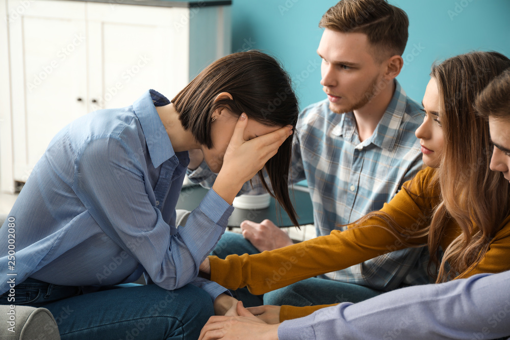 Obraz premium Group of people calming their friend indoors