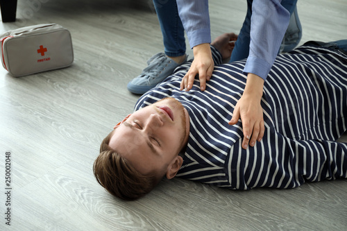 Woman providing first aid to her unconscious husband at home photo