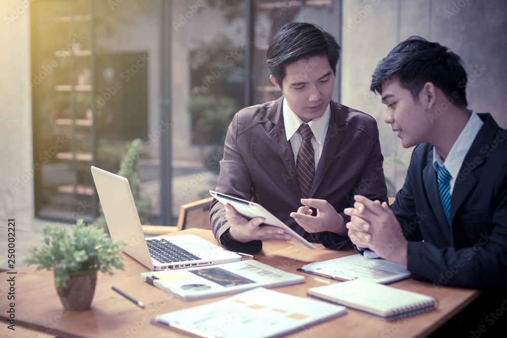 Image of two young asia businessmen using touchpad at meeting Image of two young asia businessmen using touchpad at meeting