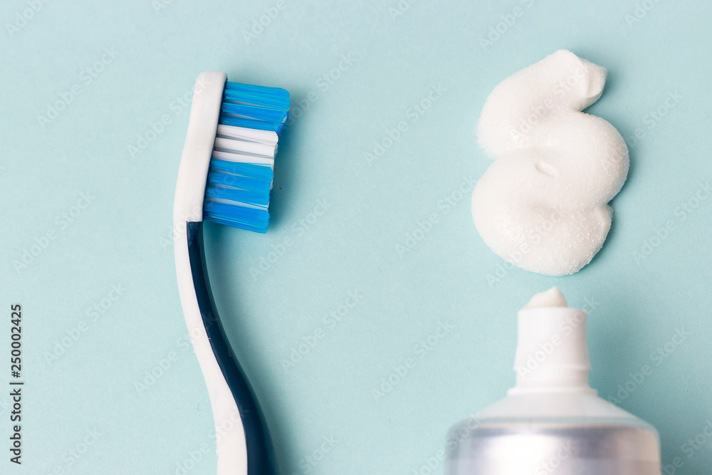 Fototapeta premium Toothpaste in tube and toothbrush on blue background. Dental hygiene concept.
