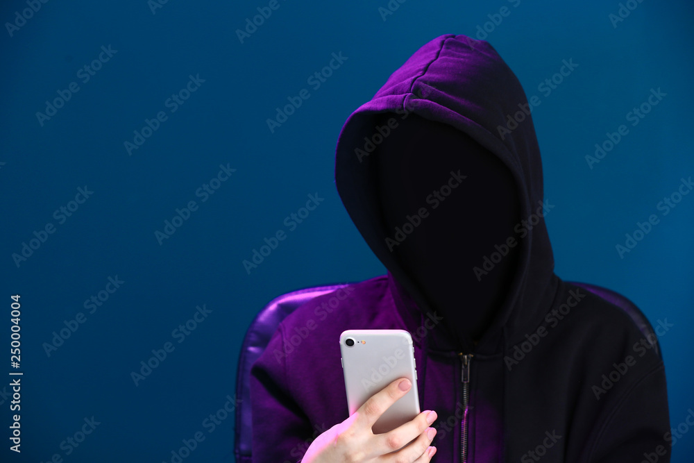 Female hacker in mask and with mobile phone on color background Female hacker in mask and with mobile phone on color background