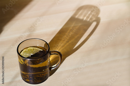 Cup of green herbal tea with lemon. Healthy diet. Shadow with sun. photo