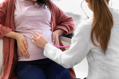 Young doctor examining pregnant woman in clinic