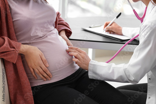 Young doctor examining pregnant woman in clinic