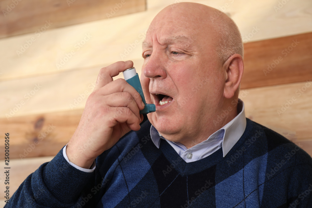 Senior man with inhaler having asthma attack at home Senior man with inhaler having asthma attack at home