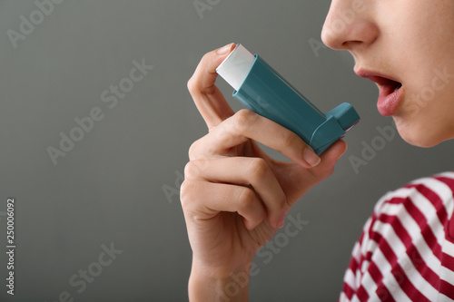 Young woman using inhaler a...