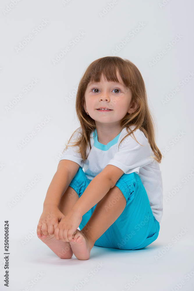 closeup image of a pretty little girl casual clothing sitting on the floor in blue trousers and white t-shirt isolated on white background closeup image of a pretty little girl casual clothing sitting on the floor in blue trousers and white t-shirt isolated on white background