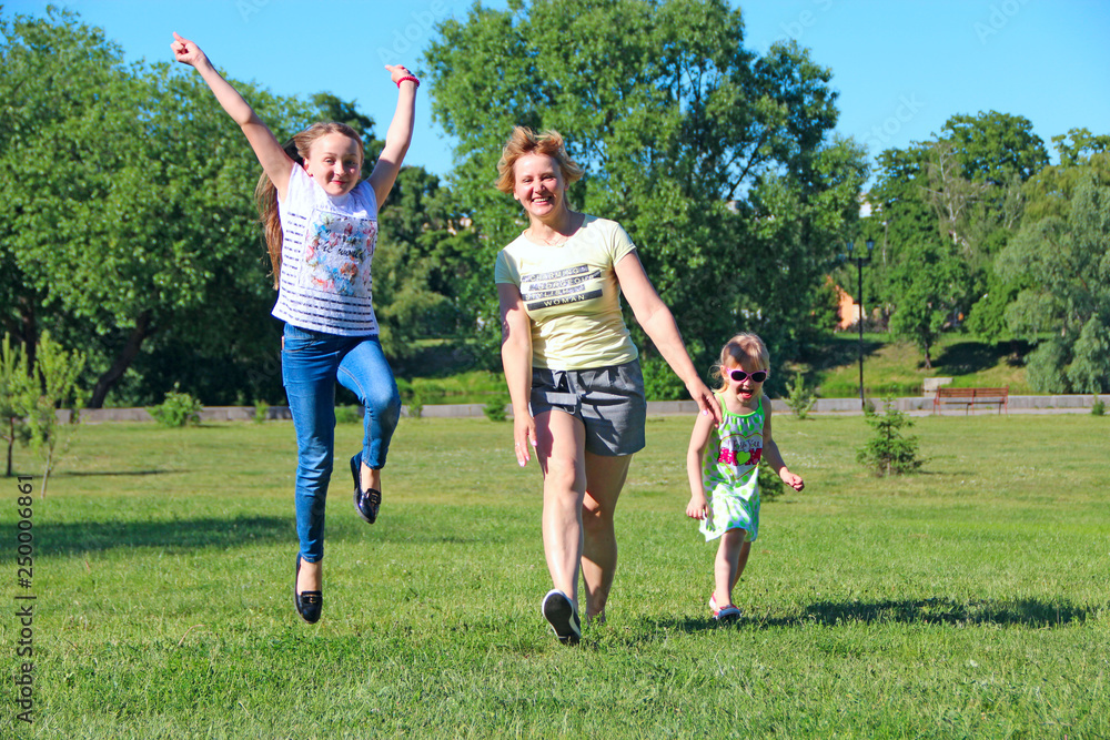 Happy mother having fun jumping with her daughters on green grass Happy mother having fun jumping with her daughters on green grass