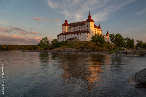 Last sun rays casting a warm light on Lacko castle with reflection in the waters of lake Vanern, Lidköping, Sweden