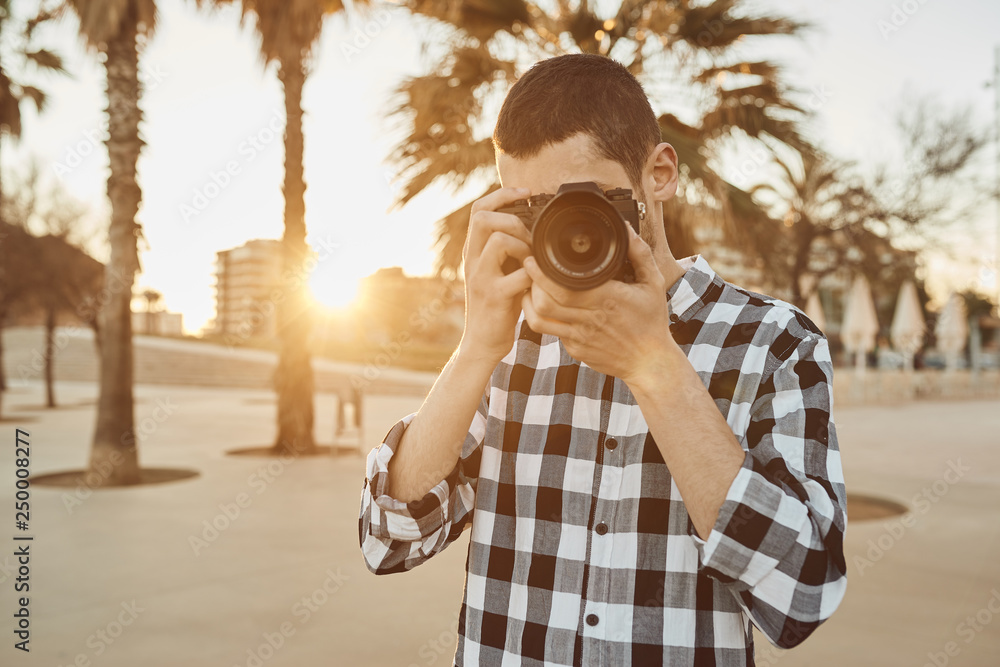 un chico joven fotógrafo utiliza una cámara sin espejo en un atardecer en  Badalona, Barcelona Stock Photo | Adobe Stock