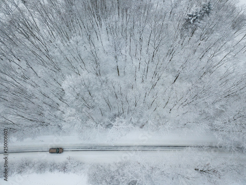 Aerial view of a car on winter road in the forest photo