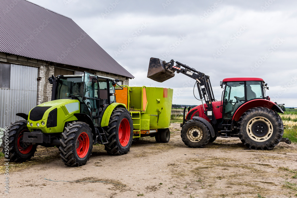 Tractor with front end loader loads the food into a distributor of animal feed for cows