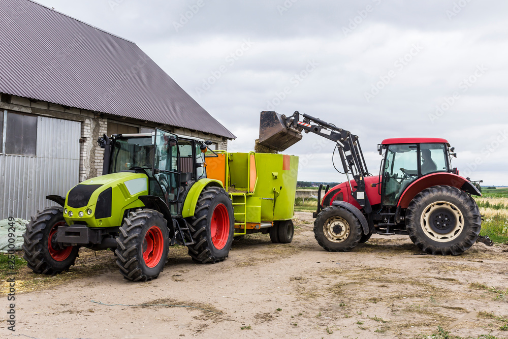 Tractor with front end loader loads the food into a distributor of animal feed for cows. Necessary equipment for a dairy farm. Tractor with front end loader loads the food into a distributor of animal feed for cows. Necessary equipment for a dairy farm.