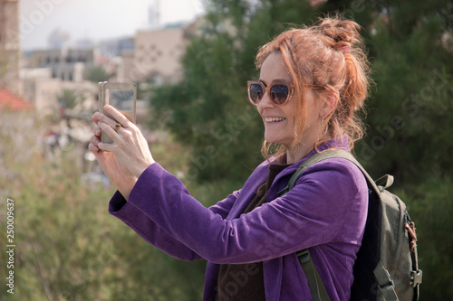 Portrait of a female tourist taking a photo on her smartphone