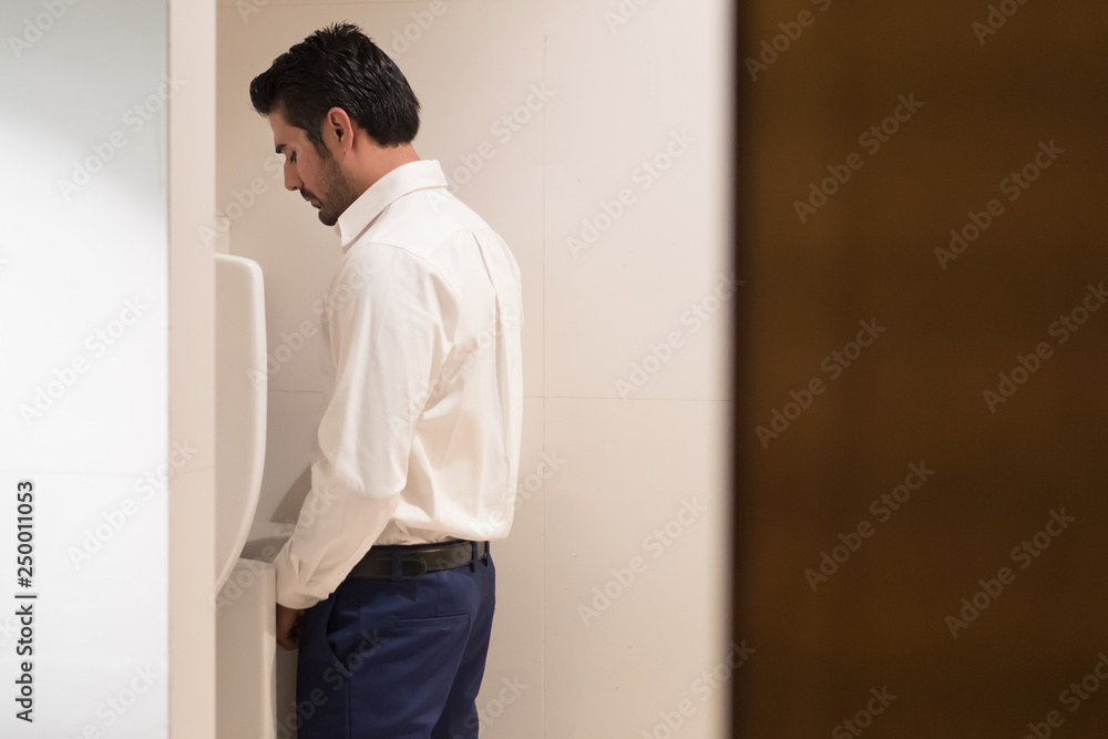 Fotografie, Obraz Asian man urinating in toilet; portrait of Indian man using water closet, WC for