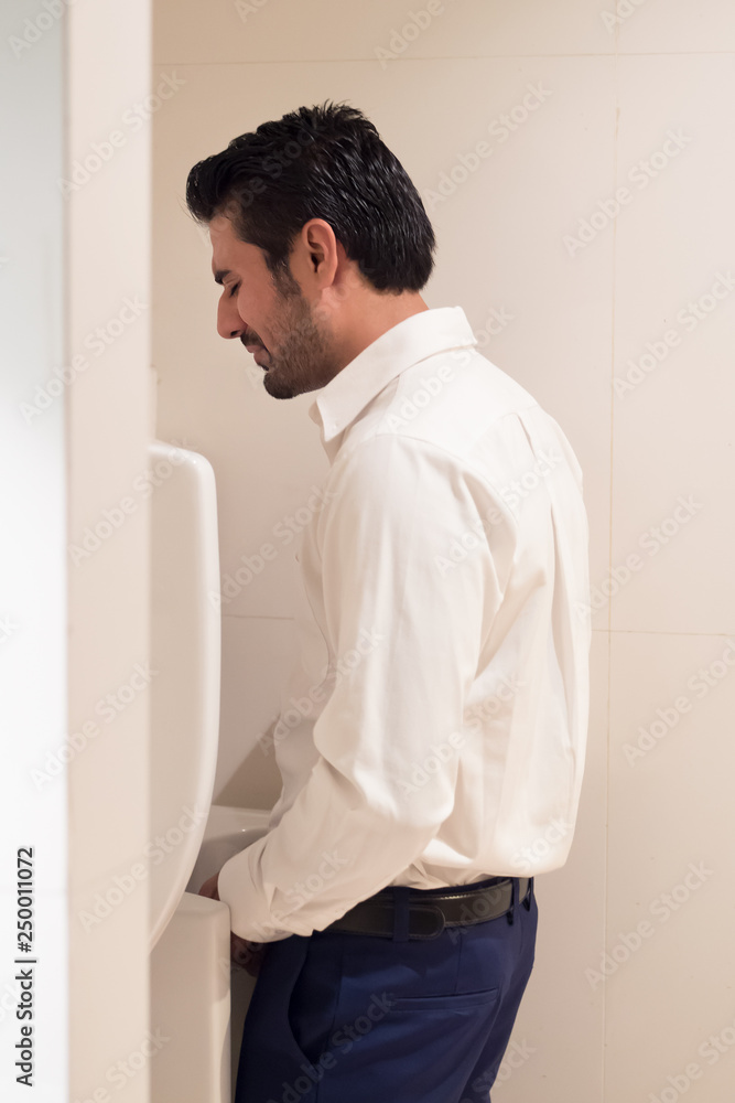 Asian man urinating in toilet; portrait of Indian man using water closet,  WC for peeing; concept of health care, prostate cancer, urethritis, UTI or  urinary tract infection; Asian adult man model Stock