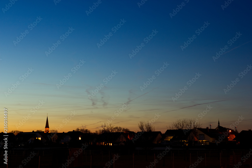 Wolkenspiel über dem Kirchturm beim Sonnenuntergang