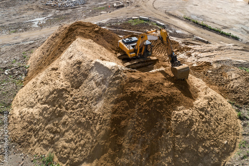 Tracked excavator overloads the sand from the embankment