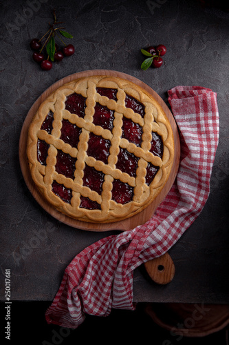 cherry pie on a chopping board with fresh cherries