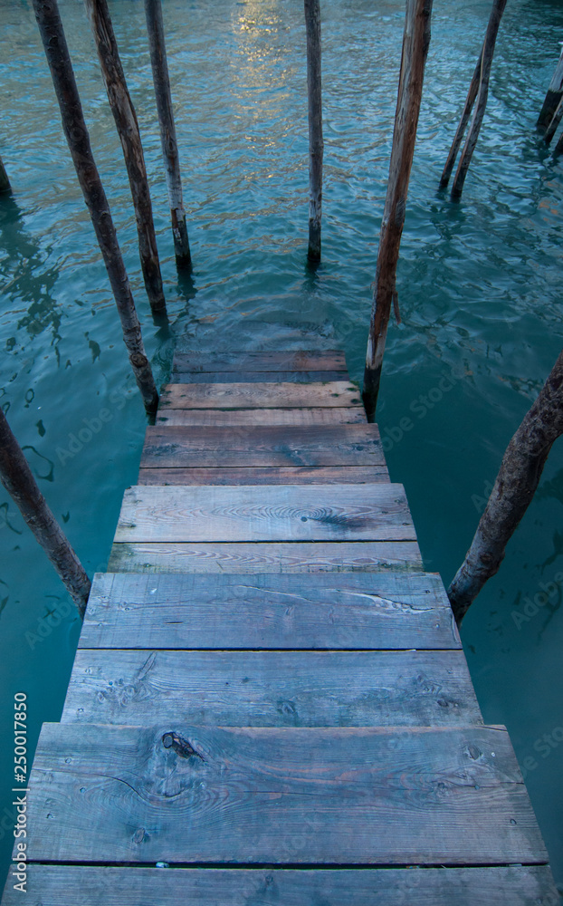 Fototapeta premium Wooden stairs into a canal in Venice