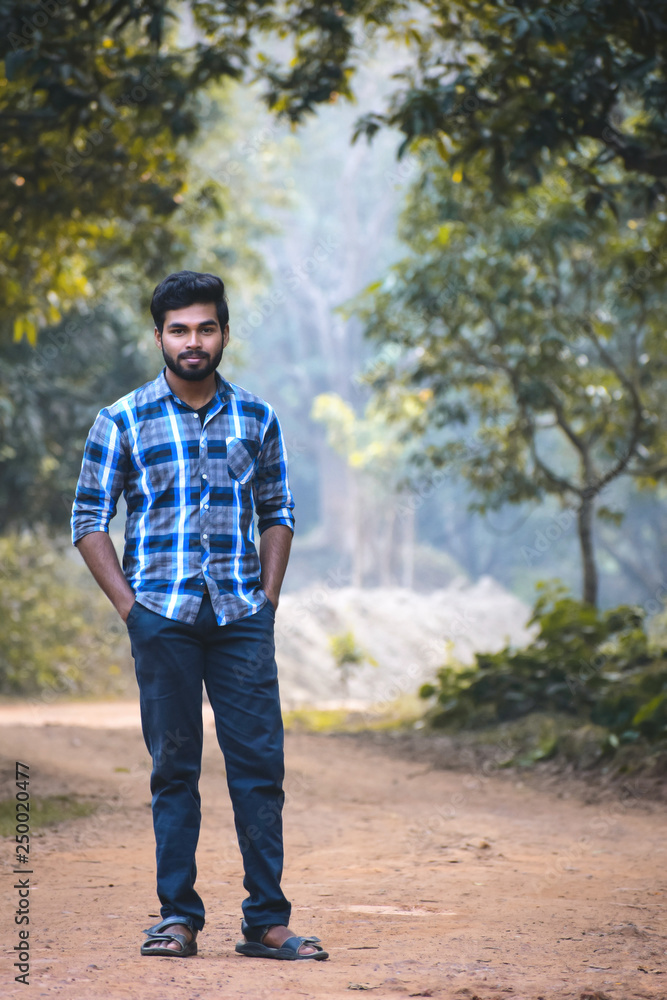 A Indian young boy standing in a forest and looking at other side A Indian young boy standing in a forest and looking at other side